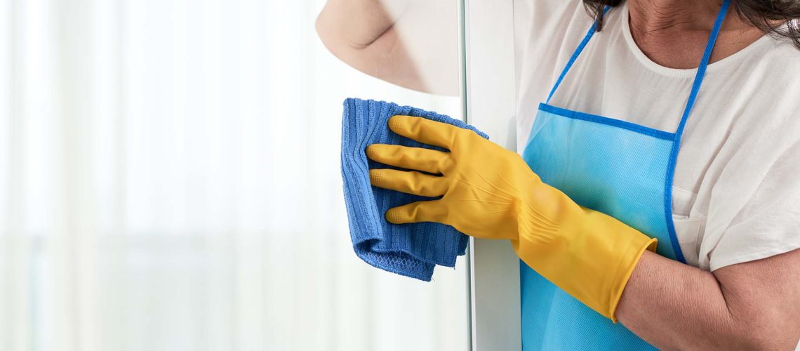 Cropped image of woman cleaning window with rag